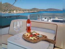 A beautifully arranged charcuterie board with wine glasses and a bottle of rosé on a boat, perfect for a relaxing day on the water.