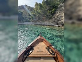 A stunning view from the front of a boat, showcasing clear turquoise waters and a swimmer in the background, perfect for exploring serene coastal landscapes.