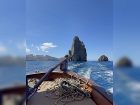 A stunning view from a boat showcasing dramatic rock formations against a clear blue sky, perfect for capturing the beauty of coastal adventures.