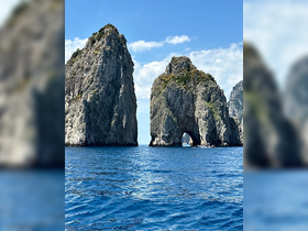 A stunning view of the iconic rock formations at Capri, Italy, showcasing the breathtaking coastline and crystal-clear waters — a must-see destination for boat tours.