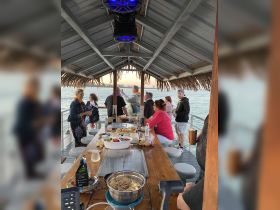 Guests enjoy a vibrant dining experience on a boat, featuring a variety of food and drinks, perfect for social gatherings and celebrations on the water.