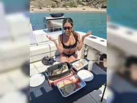 A woman enjoys a delicious meal prepared on board, showcasing fresh fish and sides, perfect for a relaxing day on the water.