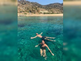A couple enjoys a refreshing swim in crystal-clear waters, surrounded by stunning natural scenery — a perfect summer getaway.