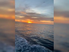 A stunning sunset over the ocean, captured from a boat, showcasing the tranquil beauty of the water and sky.