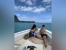 A couple enjoys the scenic view from the bow of a boat, perfect for a relaxing day on the water and snorkeling adventures.