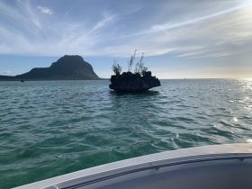 A stunning view of a rocky island and mountain backdrop, captured from a boat on tranquil waters — perfect for showcasing the beauty of coastal adventures.