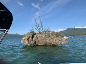A scenic view featuring a rocky island with a boat cruising nearby, showcasing the beautiful coastline and clear waters — perfect for exploring nature on the water.