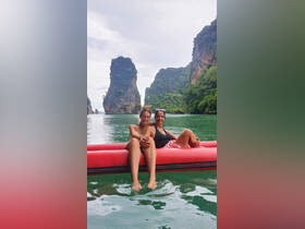 A mother and daughter enjoy a serene moment on a floating mat in a stunning bay, surrounded by towering limestone cliffs — a perfect family adventure in nature.