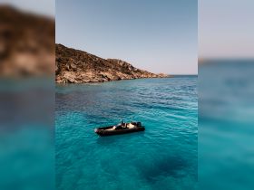 A sleek speedboat glides through crystal-clear waters, surrounded by stunning rocky coastline — perfect for exploring hidden coves and enjoying the beauty of the sea.
