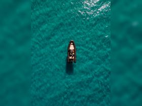 Aerial view of a boat navigating through crystal-clear turquoise waters, showcasing the beauty of marine adventures.