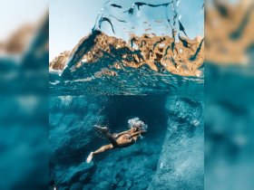 A stunning underwater shot captures a swimmer gliding gracefully through crystal-clear waters, showcasing the beauty of aquatic adventures.