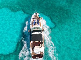 Aerial view of a boat cruising through stunning turquoise waters, showcasing a lively group enjoying their time on the water.