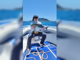 An angler proudly displays his catch aboard a boat, showcasing the thrill of fishing in beautiful ocean waters.
