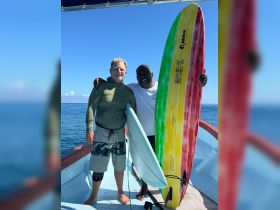 Two friends pose with their surfboards on a boat, ready for an exciting day of surfing in the ocean. Perfect for adventure seekers and water sports enthusiasts.