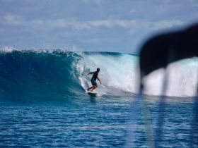 A surfer skillfully rides a powerful wave in crystal-clear waters, capturing the thrill of ocean adventures and water sports.