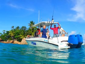 A lively group celebrates aboard a fishing boat in tropical waters, showcasing the joy of a fun day on the water.