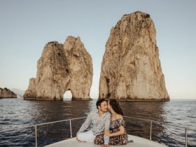 A couple shares a romantic moment on a boat near iconic rock formations, perfect for sunset cruises and memorable experiences on the water.