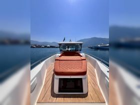 A view of the helm and seating area on a sleek boat, showcasing a comfortable sunbed and the inviting waters of the marina.