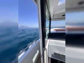 A view of the interior helm area of a boat, showcasing sleek design and a glimpse of the open water, perfect for navigating the seas.