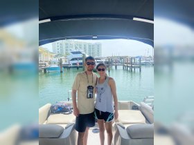 A couple poses together on a boat at the marina, capturing a moment of joy and adventure on the water.