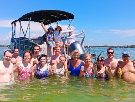 A lively group enjoys a fun day in the water, celebrating with drinks and snorkeling gear near their pontoon boat — the perfect backdrop for summer adventures.