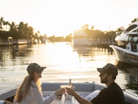 A couple enjoys a romantic toast with cocktails on a boat at sunset, creating the perfect atmosphere for memorable moments on the water.