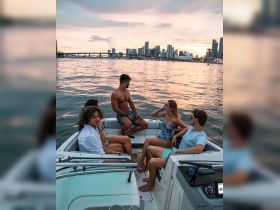 A lively group enjoys a sunset boat ride, surrounded by the stunning Miami skyline — perfect for social gatherings and memorable outings on the water.
