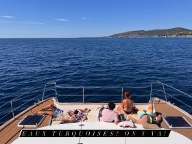 A group of friends relaxes on the deck of a yacht, soaking up the sun and enjoying the stunning ocean views — the perfect getaway for sunbathing and relaxation.