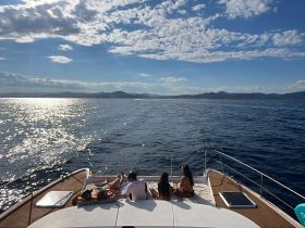 A group of friends relaxes on the deck of a yacht, soaking up the sun and enjoying the stunning ocean views — the perfect setting for a day on the water.