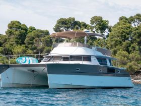 A sleek catamaran anchored in clear waters, showcasing its modern design and spacious layout, perfect for leisurely cruises or family outings.