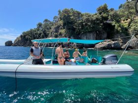 A lively group enjoys a day on the water aboard a boat, surrounded by stunning coastal scenery — perfect for summer adventures and relaxation.