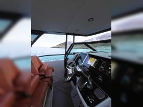 A sleek view of the helm area inside a modern boat, featuring comfortable seating and advanced navigation equipment, perfect for a smooth sailing experience.