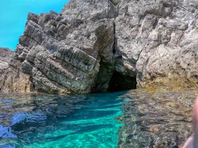 A stunning view of a rocky cave entrance surrounded by crystal-clear waters, perfect for exploring coastal landscapes and natural wonders.
