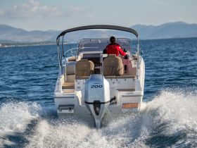 A sleek speedboat glides through the water, showcasing its powerful engine and stylish design, perfect for thrilling adventures on the open sea.
