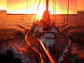 A stunning sunset view from the deck of a yacht, capturing the beauty of sailing on tranquil waters — perfect for romantic evenings or sunset cruises.