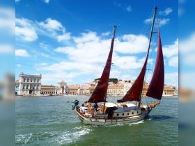 A beautiful sailboat navigates the waters with a stunning cityscape in the background, showcasing the charm of a vibrant coastal destination.