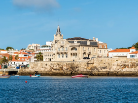 A scenic view of a coastal area featuring a historic building and boats in the water, though the image lacks clarity.