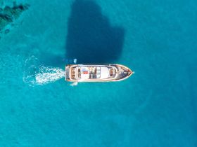 A stunning aerial view of a luxurious yacht cruising through crystal-clear turquoise waters, perfect for showcasing the beauty of boating adventures.