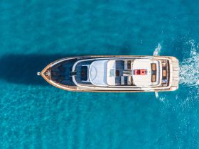 A stunning aerial view of a luxurious yacht cruising through crystal-clear turquoise waters, perfect for upscale charters and leisurely escapes.