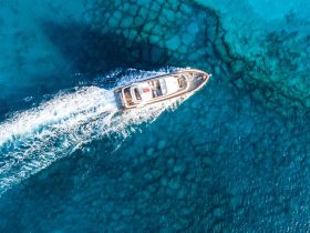 A stunning aerial view of a yacht cruising through crystal-clear turquoise waters, showcasing the beauty of boating adventures.