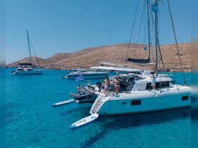 A lively group enjoys a sunny day on a catamaran, with turquoise waters and island scenery in the background — perfect for summer adventures and island hopping.