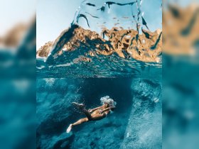 A stunning underwater shot of a swimmer gliding through crystal-clear waters, showcasing the beauty of marine adventures and the thrill of exploration.