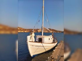 A beautiful yacht docked at the harbor, showcasing its elegant design against a serene backdrop of hills and clear skies.