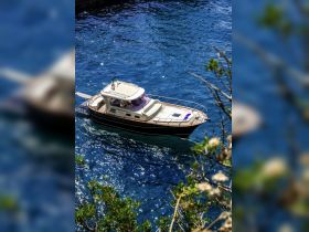A stunning aerial view of a boat cruising through crystal-clear waters, showcasing the vessel's elegant design against a vibrant blue backdrop.