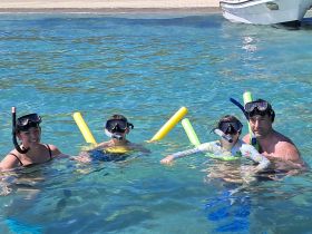 A joyful family enjoys snorkeling in crystal-clear waters, creating unforgettable memories together in a tropical paradise.