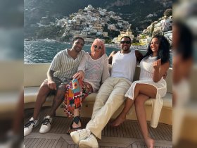 A cheerful group enjoys a moment aboard a boat with a stunning coastal backdrop, perfect for memorable gatherings and celebrations on the water.