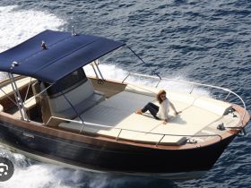 A woman relaxes on the deck of a stylish boat as it cruises through the water, showcasing the perfect blend of leisure and adventure on the open sea.