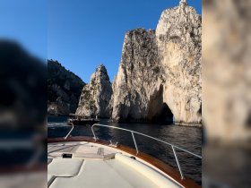 A stunning view from the bow of a boat navigating through dramatic rock formations, showcasing the natural beauty of the coastline.