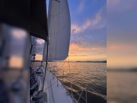 A stunning view of a sailboat navigating through tranquil waters at sunset, showcasing the beauty of sailing and the serene evening sky.