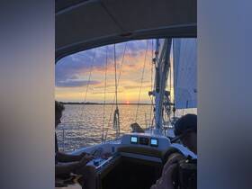 A serene sunset view from aboard a sailboat, featuring guests enjoying the moment with a guitar and camera — perfect for capturing memorable sailing experiences.